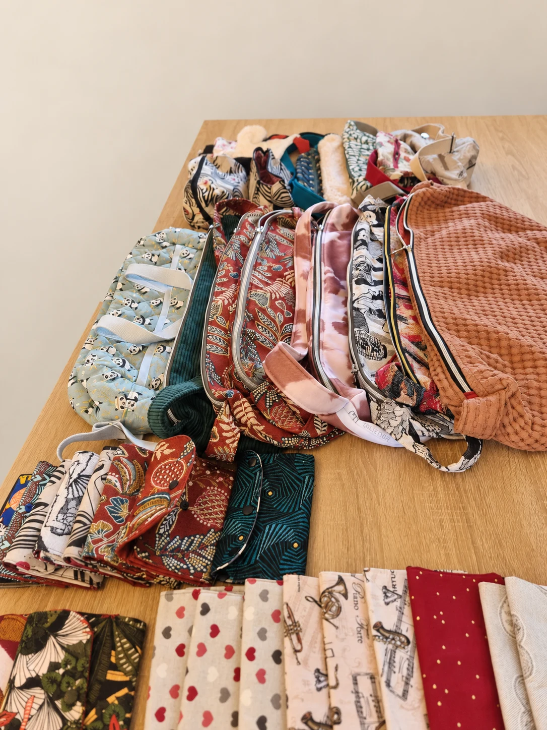 Sélection de sacs bananes, demi-lunes et petits accessoires en tissus variés, disposés sur une table