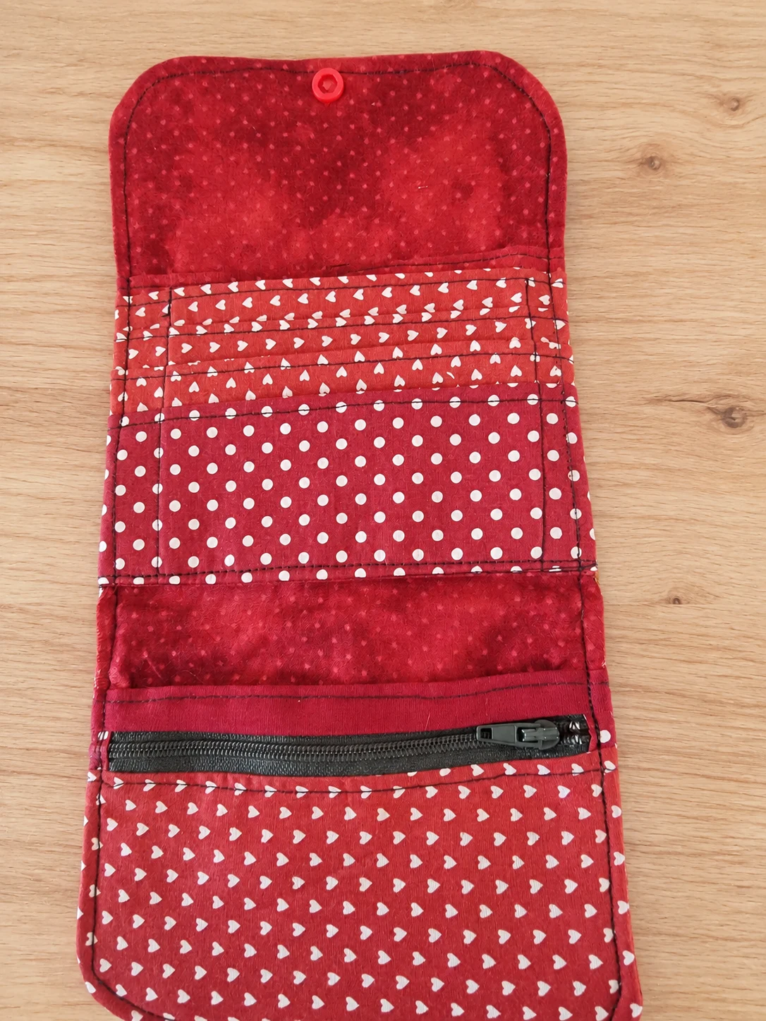 Intérieur rouge d’un porte-monnaie déplié, avec des emplacements pour cartes et une poche zippée